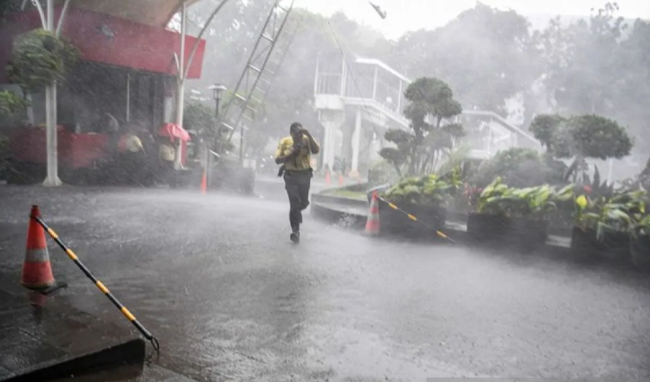 Warga membawa payung saat hujan lebat mengguyur kawasan perkotaan