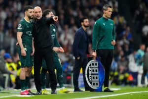 Pelatih Manchester City, Pep Guardiola berbicara dengan Rayan Ait-Nouri di laga melawan Real Madrid pada babak 16 besar Liga Champions, 12 Maret 2026. (c) AP Photo/Jose Breton